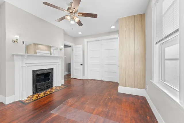 a view of a livingroom with a fireplace a ceiling fan and windows