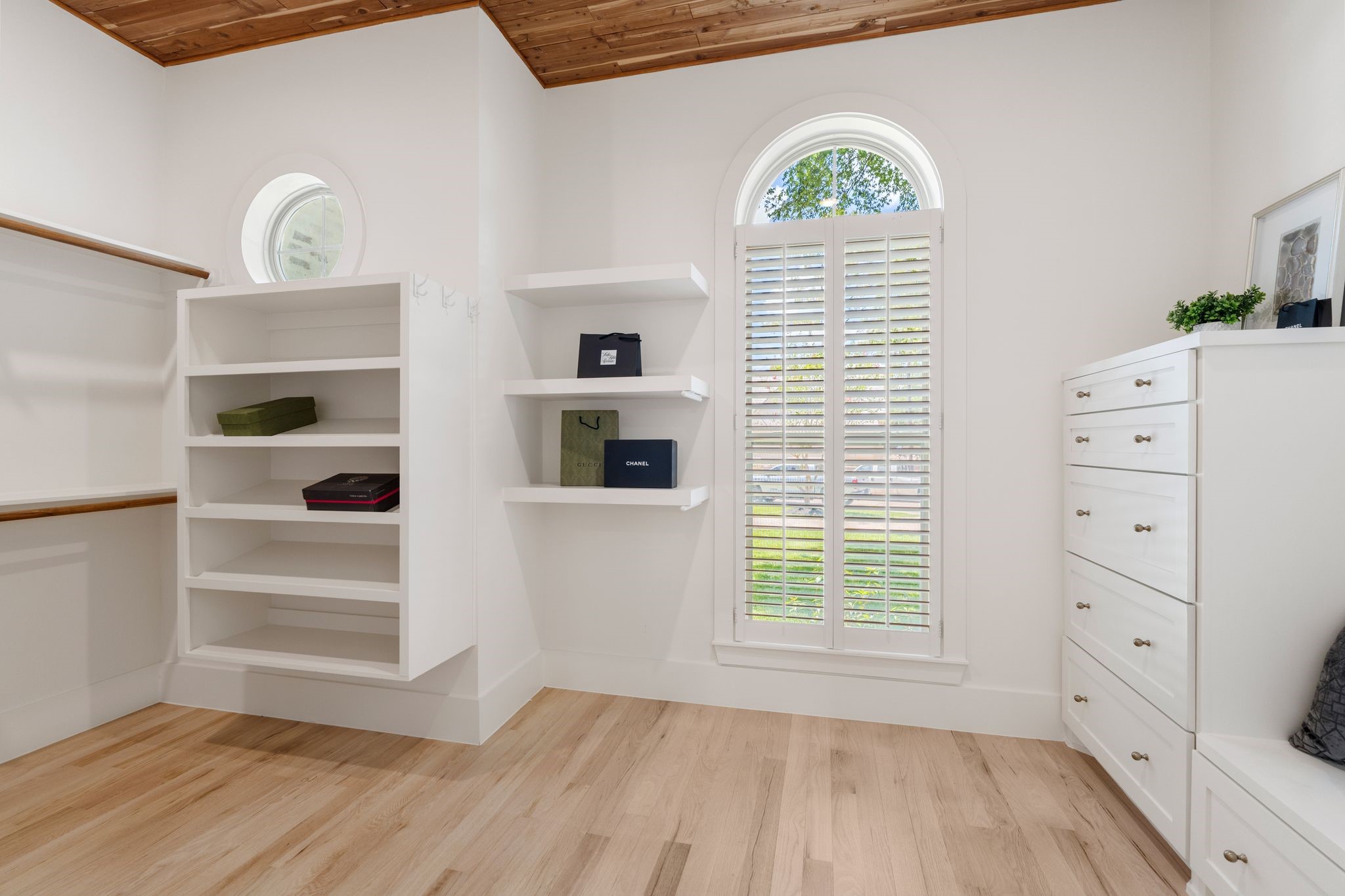 31 Hollymead Drive Spring, TX 77381 - Photo 29 of 50 This bright, spacious "His" walk-in closet features hardwood floors, built-in shelving, and ample natural light from a large arched window with shutters. The cedar paneled ceiling adds warmth and elegance.