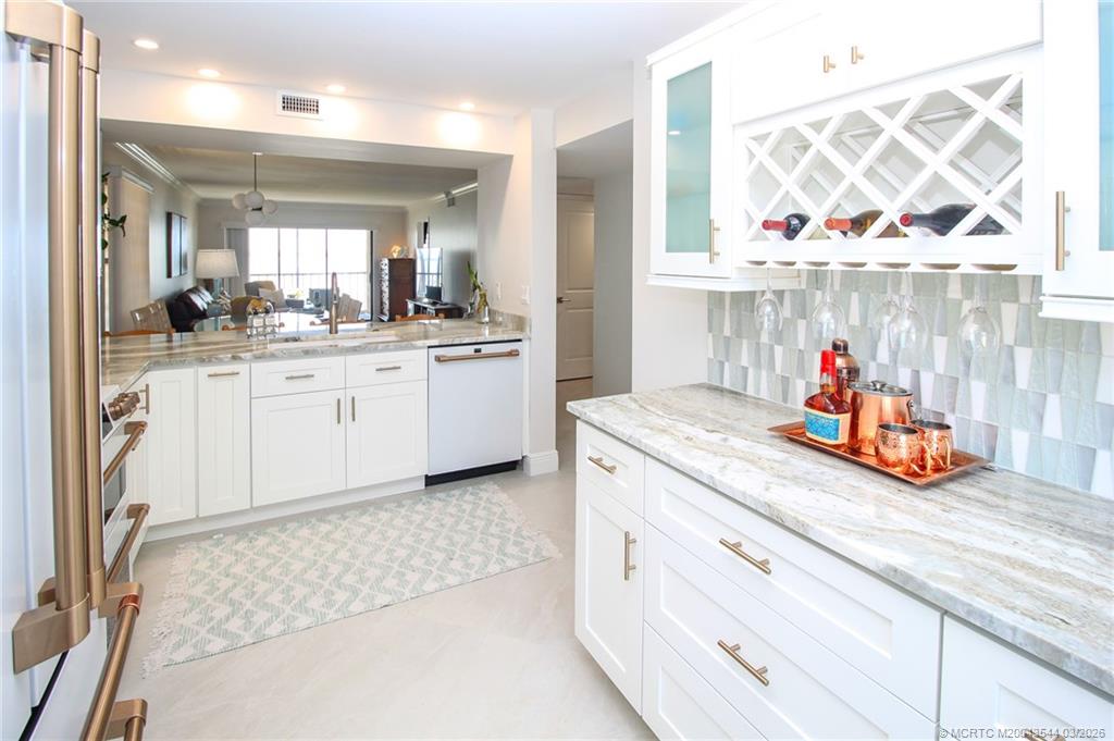 4440 Northeast Sandpebble Trace, Unit 201 Jensen Beach, FL 34957 - Photo 12 of 32 a kitchen with white cabinets and sink