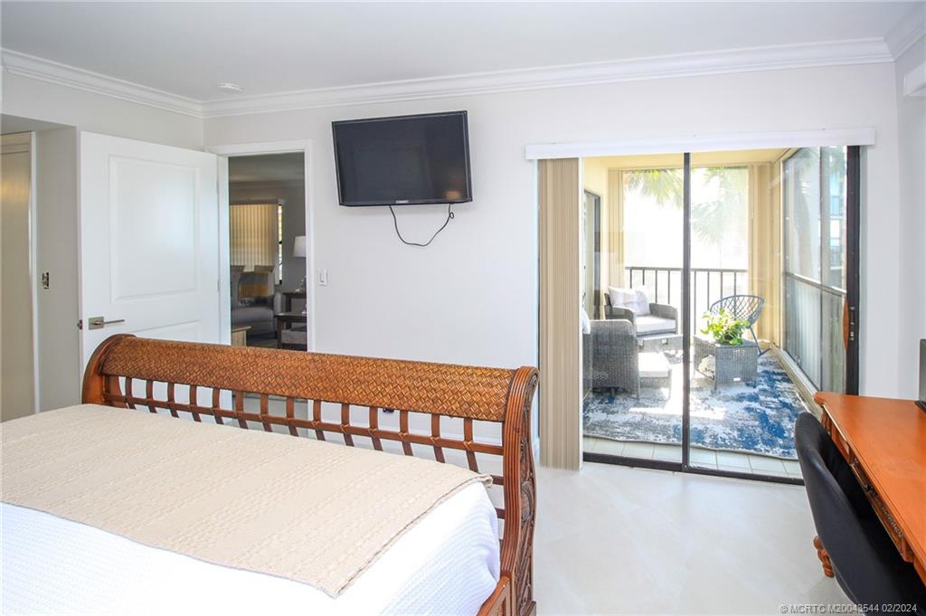 4440 Northeast Sandpebble Trace, Unit 201 Stuart, FL 34996 - Photo 16 of 23 a view of a bedroom with furniture and a flat screen tv