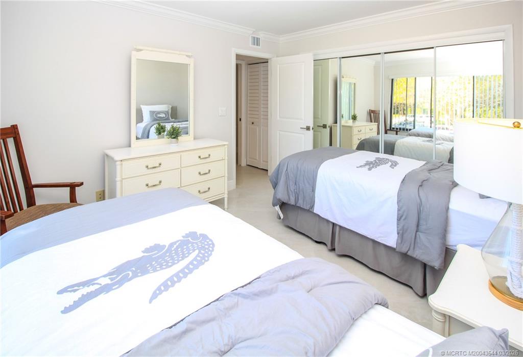 4440 Northeast Sandpebble Trace, Unit 201 Jensen Beach, FL 34957 - Photo 21 of 32 a bedroom with a bed and large windows
