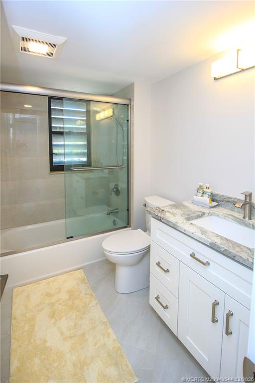 4440 Northeast Sandpebble Trace, Unit 201 Jensen Beach, FL 34957 - Photo 22 of 32 a bathroom with a granite countertop toilet a sink and a bathtub