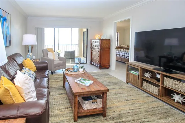 a living room with furniture a flat screen tv and a floor to ceiling window