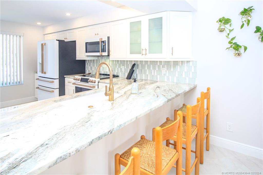 4440 Northeast Sandpebble Trace, Unit 201 Stuart, FL 34996 - Photo 9 of 23 a living room with stainless steel appliances kitchen island granite countertop furniture and a kitchen view