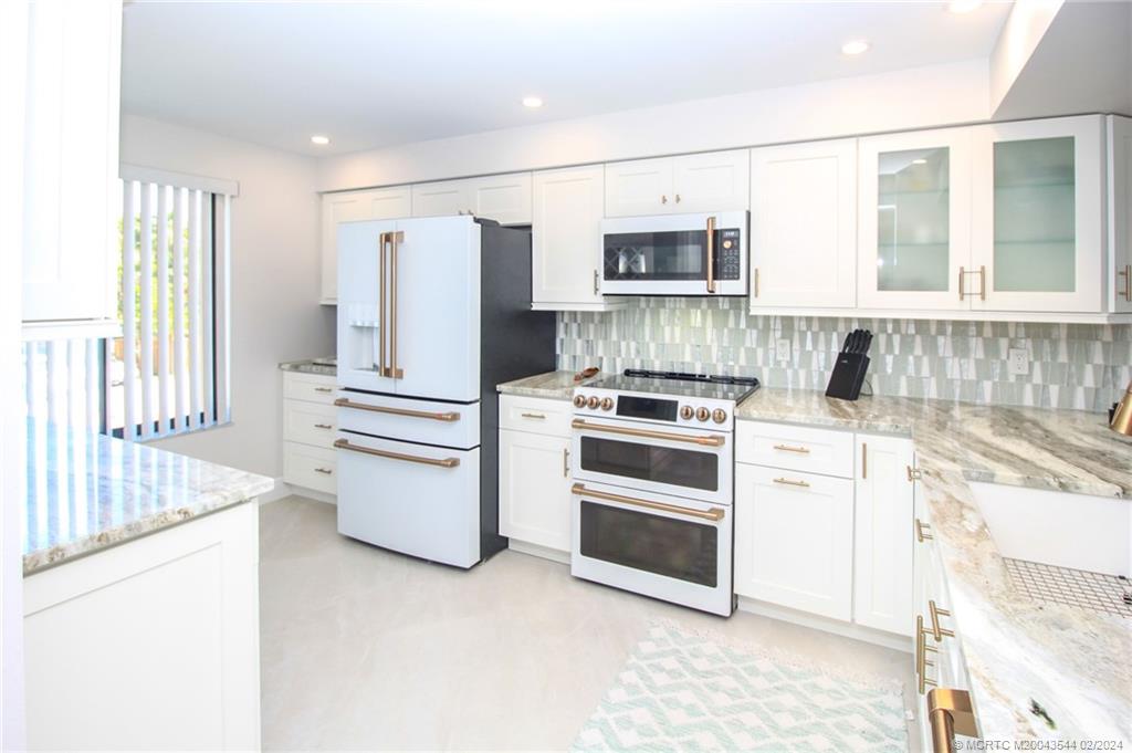 4440 Northeast Sandpebble Trace, Unit 201 Stuart, FL 34996 - Photo 10 of 23 a kitchen with stainless steel appliances a refrigerator sink and stove