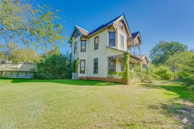 a view of a big house with a big yard and large trees