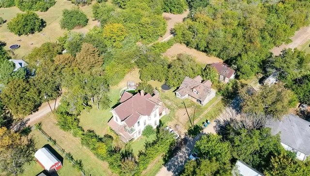 an aerial view of residential house with outdoor space and trees all around