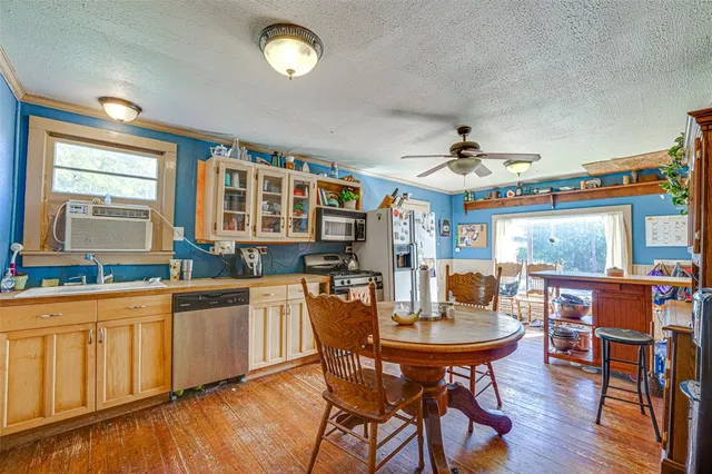 a kitchen with stainless steel appliances a dining table chairs and wooden floor