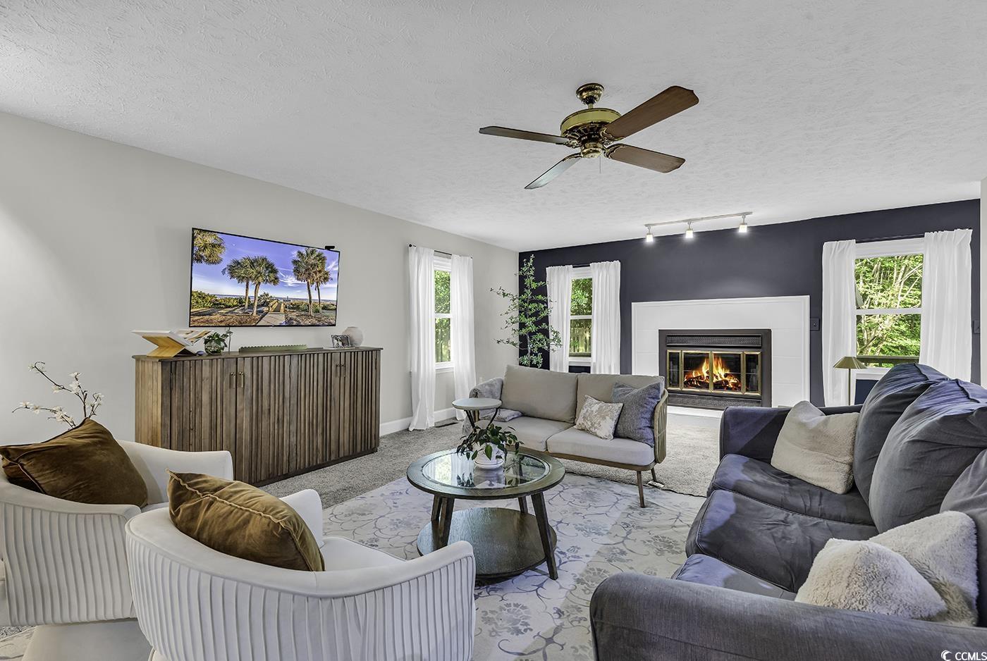 1305 Forest View Road Conway, SC 29526 - Photo 6 of 40 Carpeted living room with a textured ceiling, a ceiling fan, a glass covered fireplace, track lighting, and baseboards