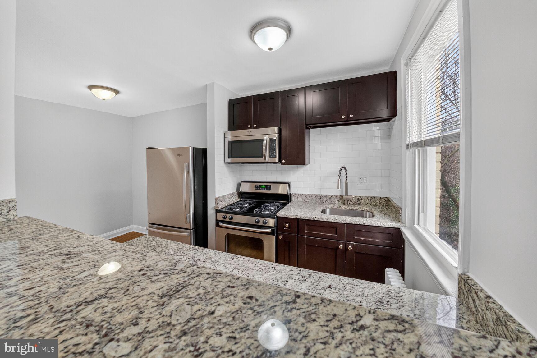 4703 Ravenswood Road, Unit 25 Riverdale, MD 20737 - Photo 8 of 12 a kitchen with stainless steel appliances granite countertop a sink stove and refrigerator