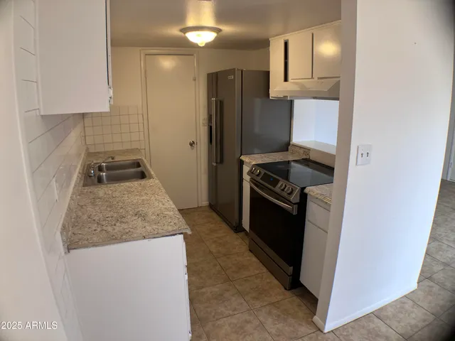 a kitchen with granite countertop stainless steel appliances a refrigerator a stove a sink and a stove