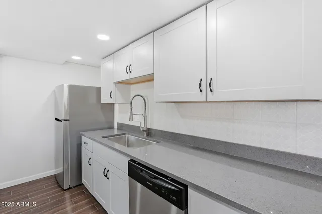 a kitchen with stainless steel appliances a sink dishwasher and white cabinets with wooden floor
