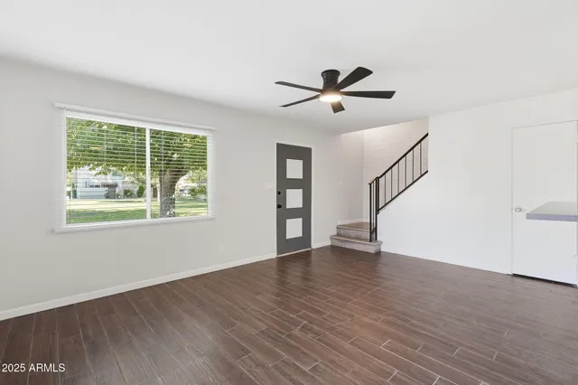 a view of an empty room with wooden floor and a window