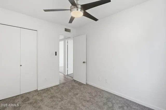 an empty room with a ceiling fan and a window
