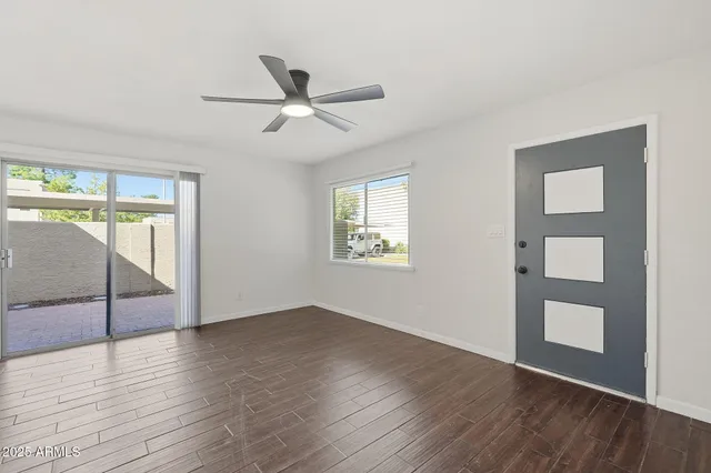 a view of an empty room with wooden floor and a window