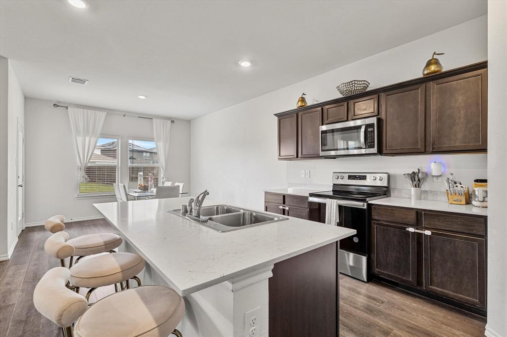 1231 Delmita Drive Forney, TX 75126 - Photo 14 of 38 a kitchen with stainless steel appliances a stove a sink a microwave a dining table and chairs