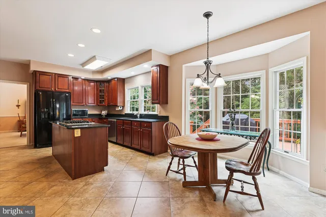 a dining room with stainless steel appliances kitchen island granite countertop a table chairs and a refrigerator