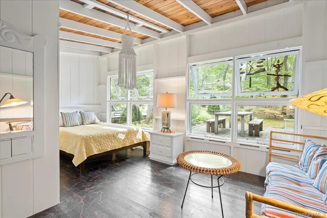 a spacious bedroom with a bed a table and chair with the large mirror