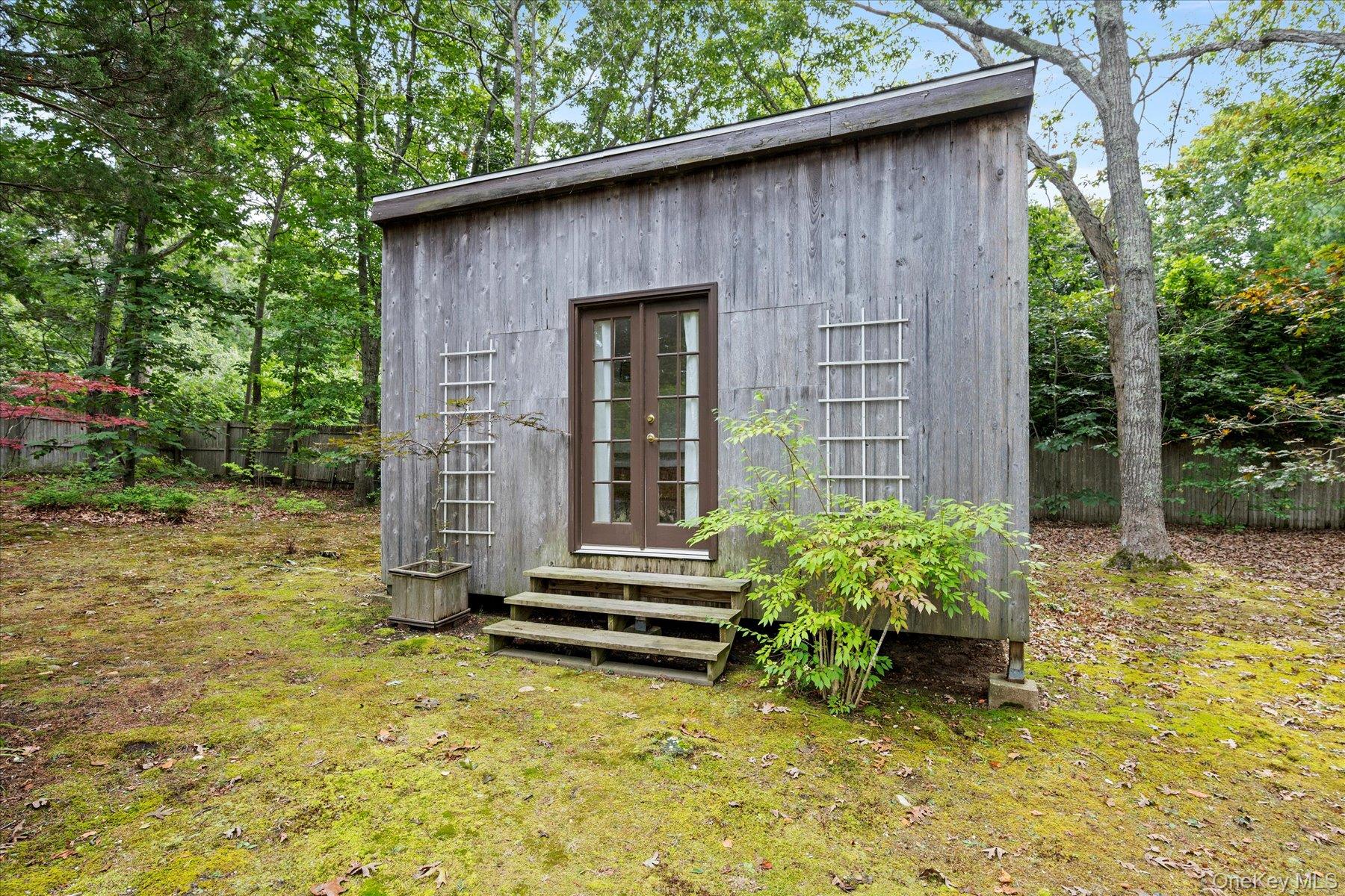46 Flaggy Hole Road East Hampton, NY 11937 - Photo 21 of 32 a backyard of a house with potted plants and large tree