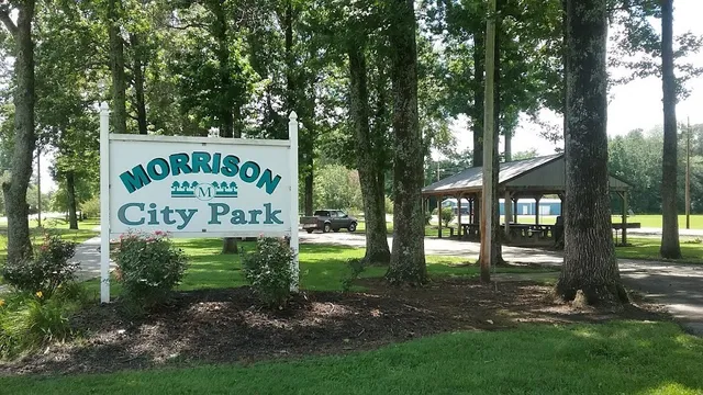 a sign that is sitting on a brick wall with large trees