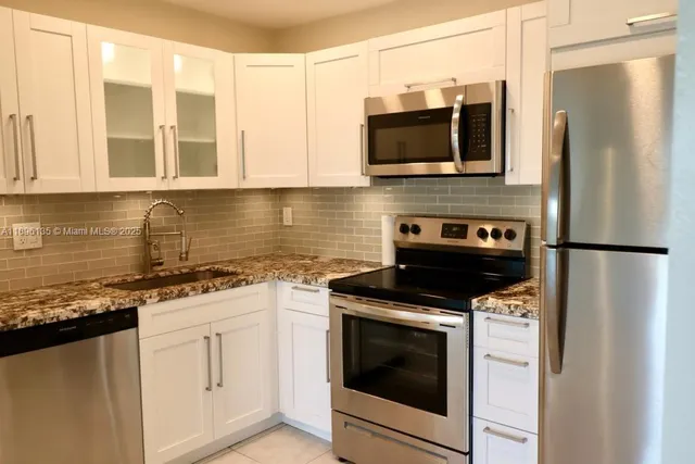 a kitchen with stainless steel appliances granite countertop a stove a microwave and a refrigerator