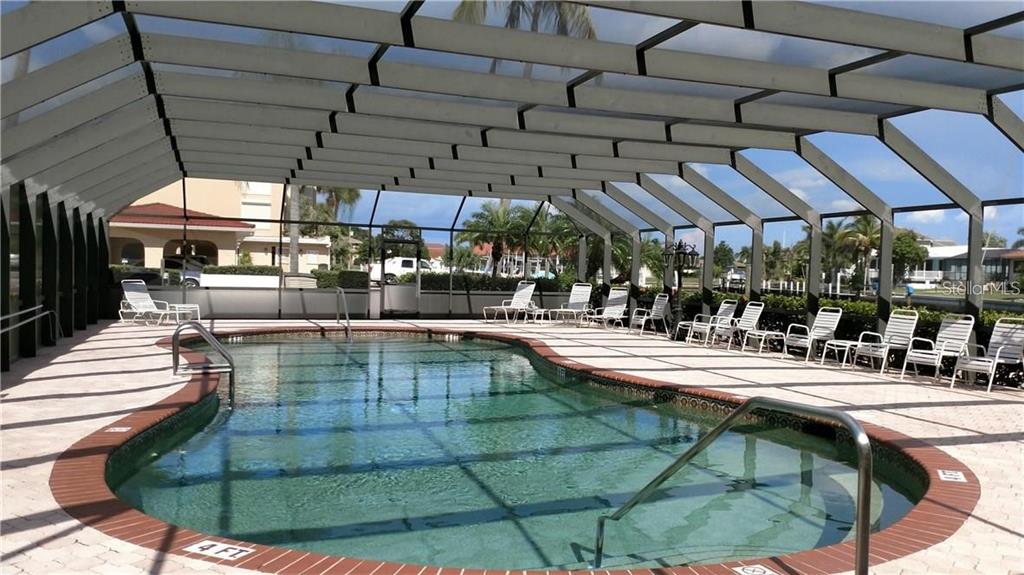 1 Colony Point Drive, Unit A5 Punta Gorda, FL 33950 - Photo 3 of 37 a view of a swimming pool with a table and chairs under an umbrella