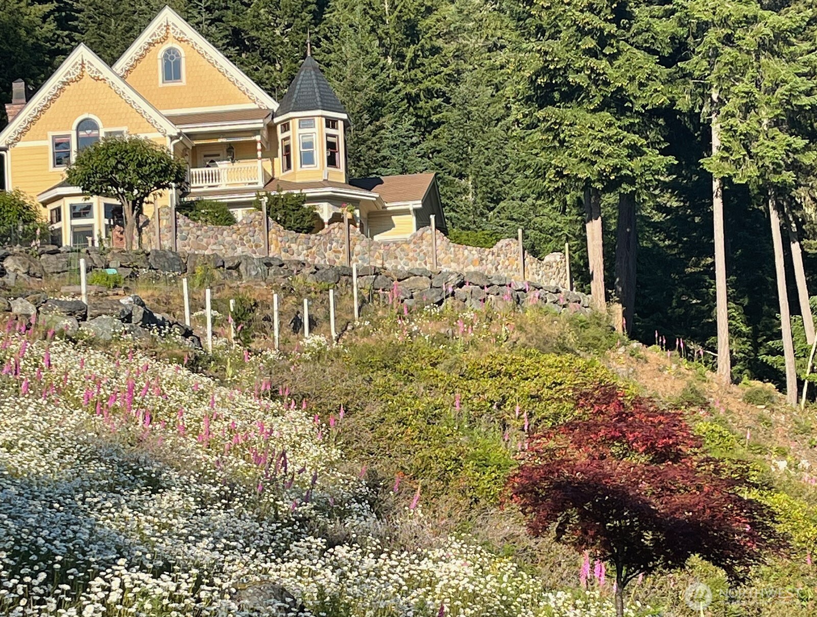 1656 Eagle Ridge Road Orcas Island, WA 98245 - Photo 2 of 40 a view of a white house with a yard and lawn chairs under an umbrella