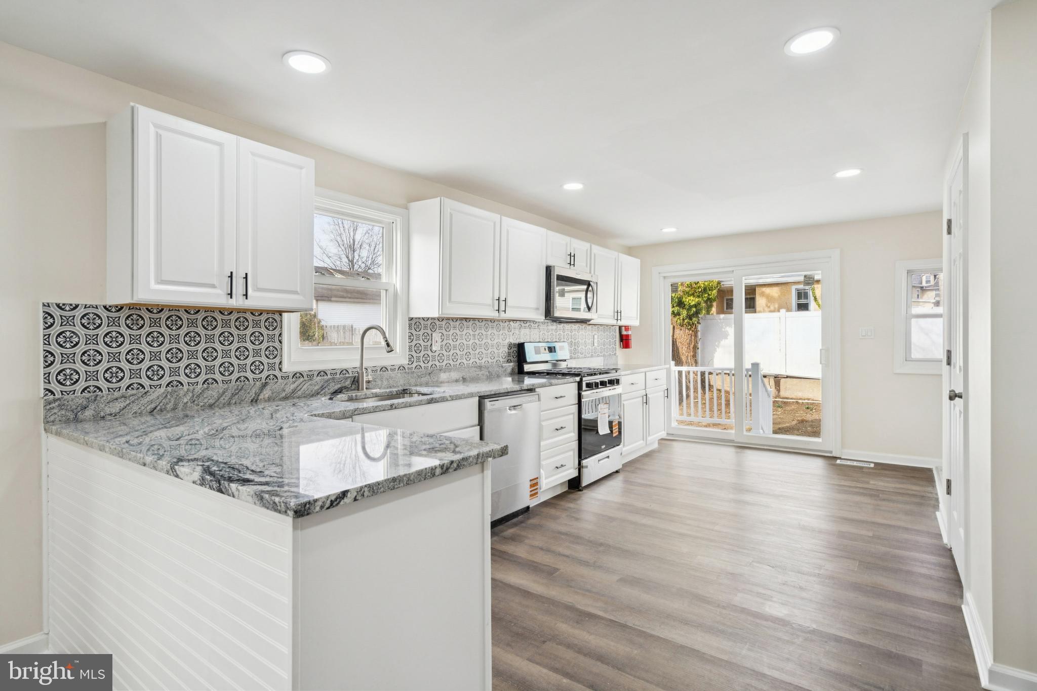 457 Wesley Avenue Pitman, NJ 08071 - Photo 11 of 25 a kitchen with stainless steel appliances granite countertop a sink stove and white cabinets with wooden floor