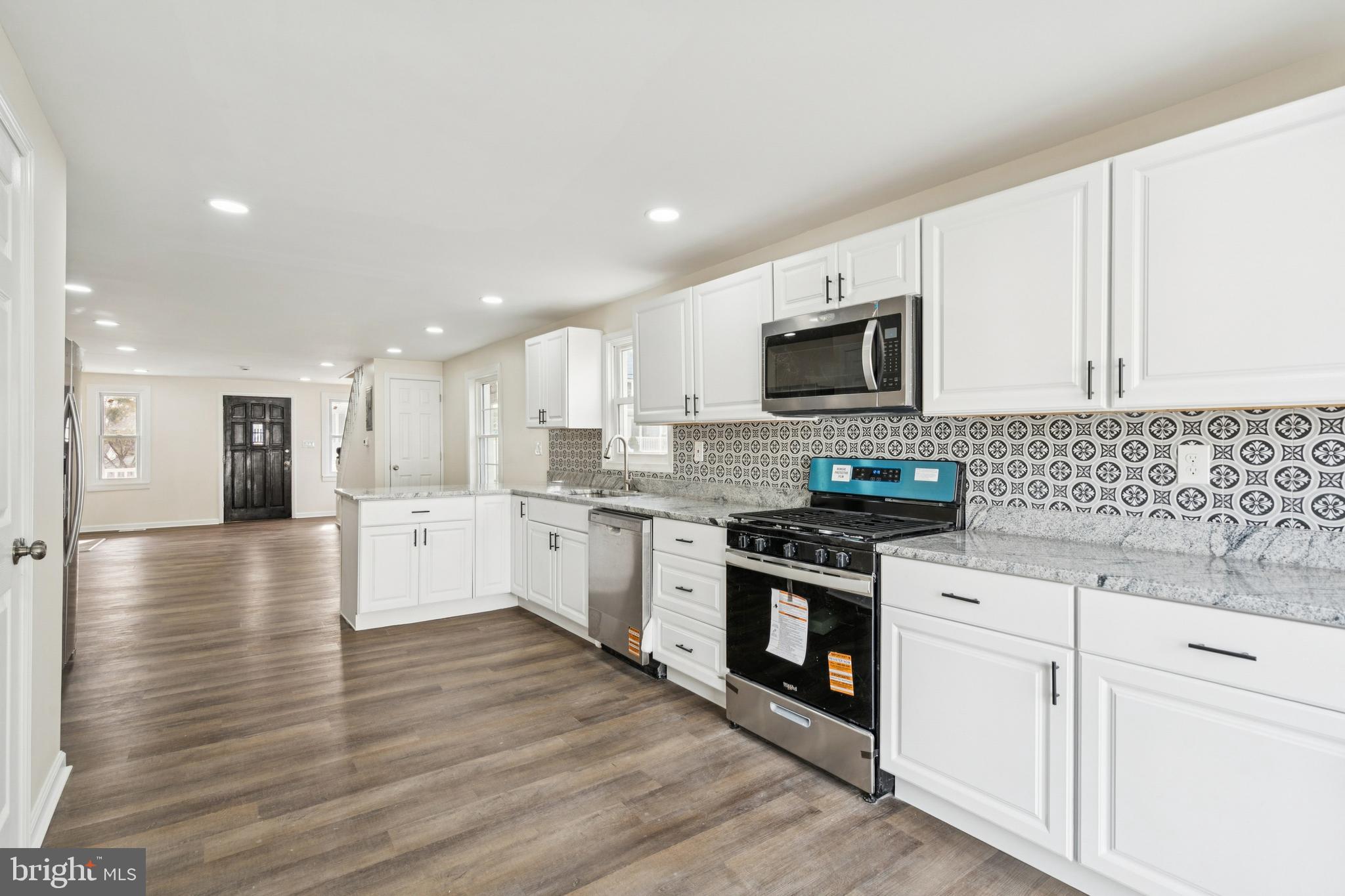 457 Wesley Avenue Pitman, NJ 08071 - Photo 12 of 25 a kitchen with granite countertop a stove top oven a sink dishwasher and a refrigerator with wooden floor