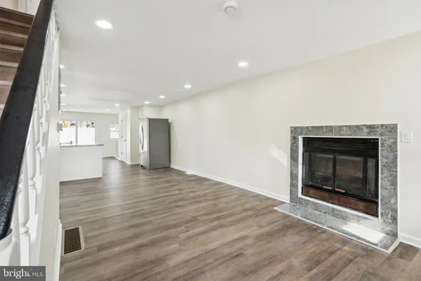 an empty room with wooden floor fireplace and windows