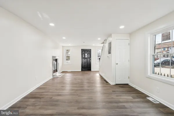 a view of an empty room with wooden floor and windows