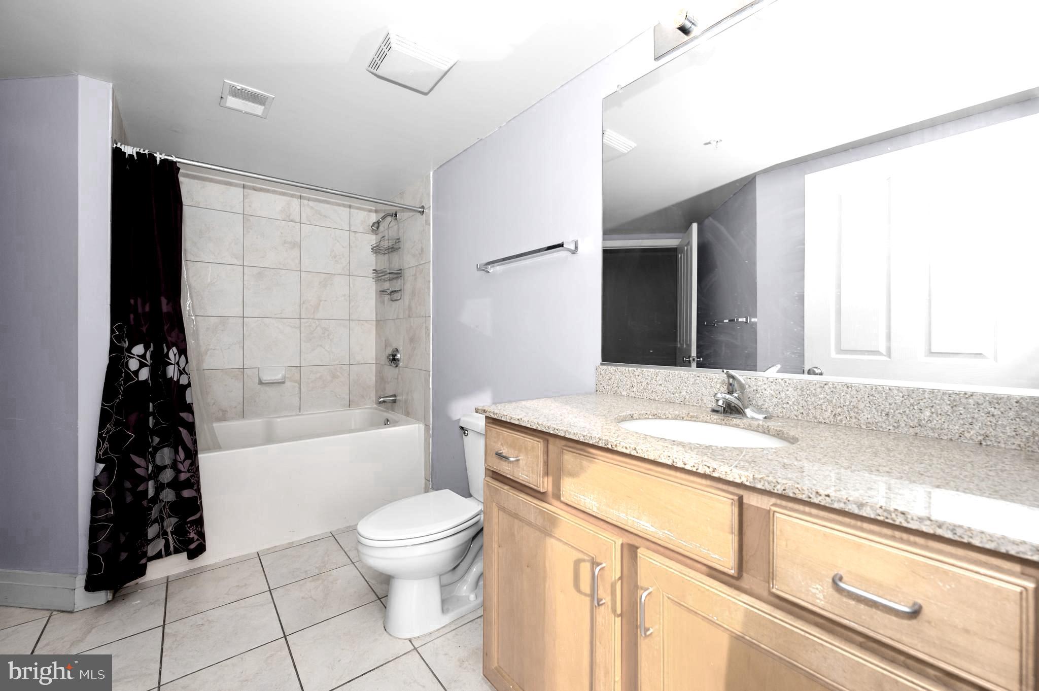 414 Water Street, Unit 2805 Baltimore, MD 21202 - Photo 11 of 24 a bathroom with a granite countertop sink a toilet and bathtub