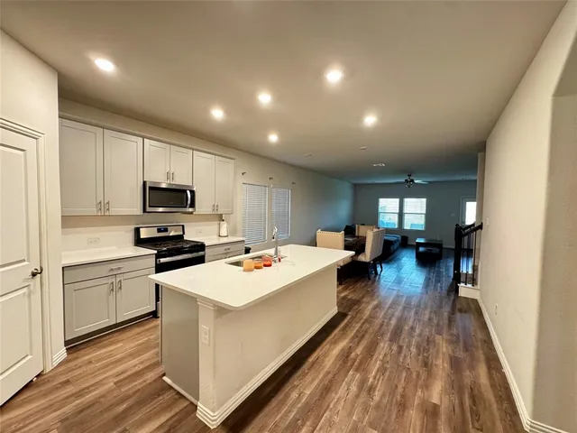 a kitchen that has a lot of cabinets a sink and wooden floor