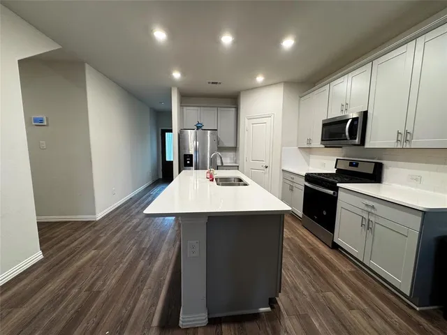 a kitchen with kitchen island a sink counter top space stainless steel appliances and cabinets