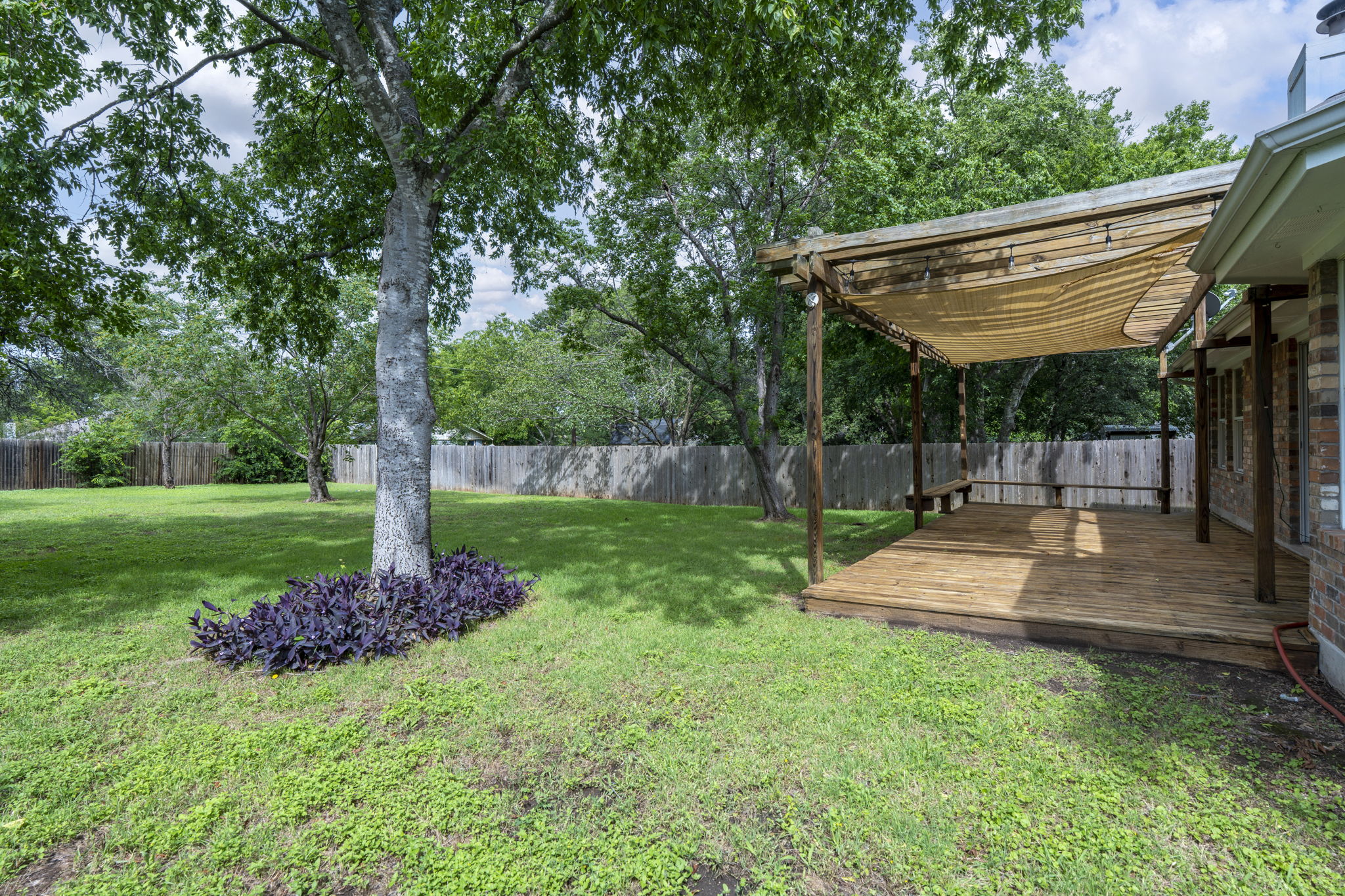7172 Ridge Oak Road Austin, TX 78749 - Photo 9 of 40 A spacious yard features mature trees and a charming covered deck, perfect for outdoor enjoyment.