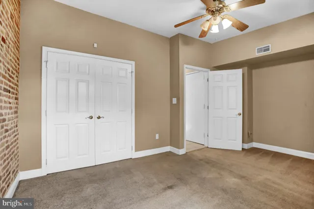an empty room with a chandelier fan and closet area