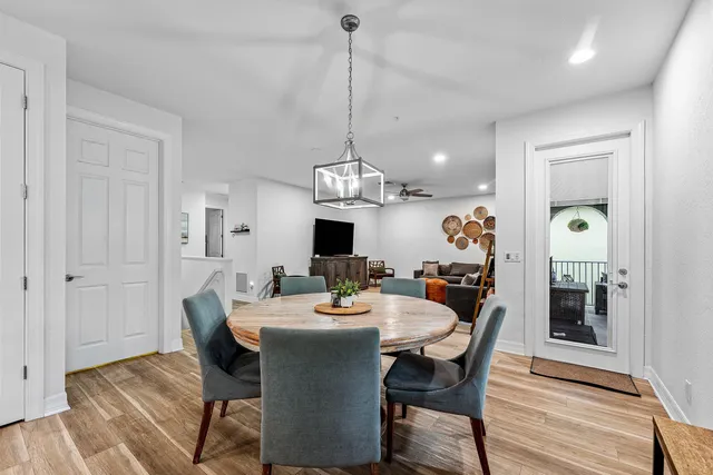 a dining room with wooden floor a chandelier a wooden table and chairs
