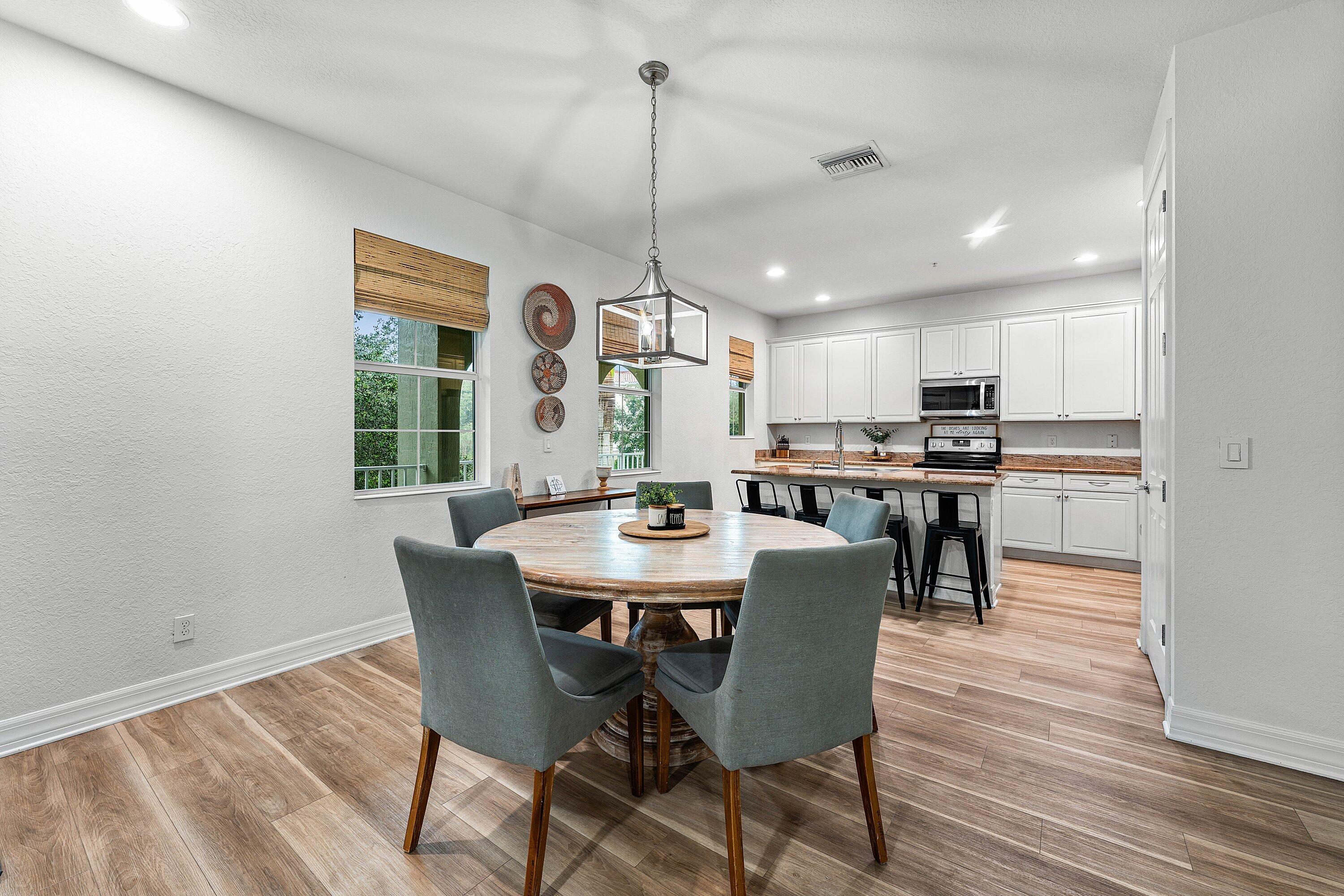1056 Community Drive Jupiter, FL 33458 - Photo 13 of 50 a view of a dining room and livingroom with furniture wooden floor a rug a painting and a chandelier