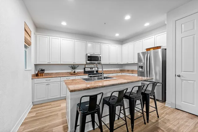 a kitchen with stainless steel appliances granite countertop a table chairs sink refrigerator and microwave