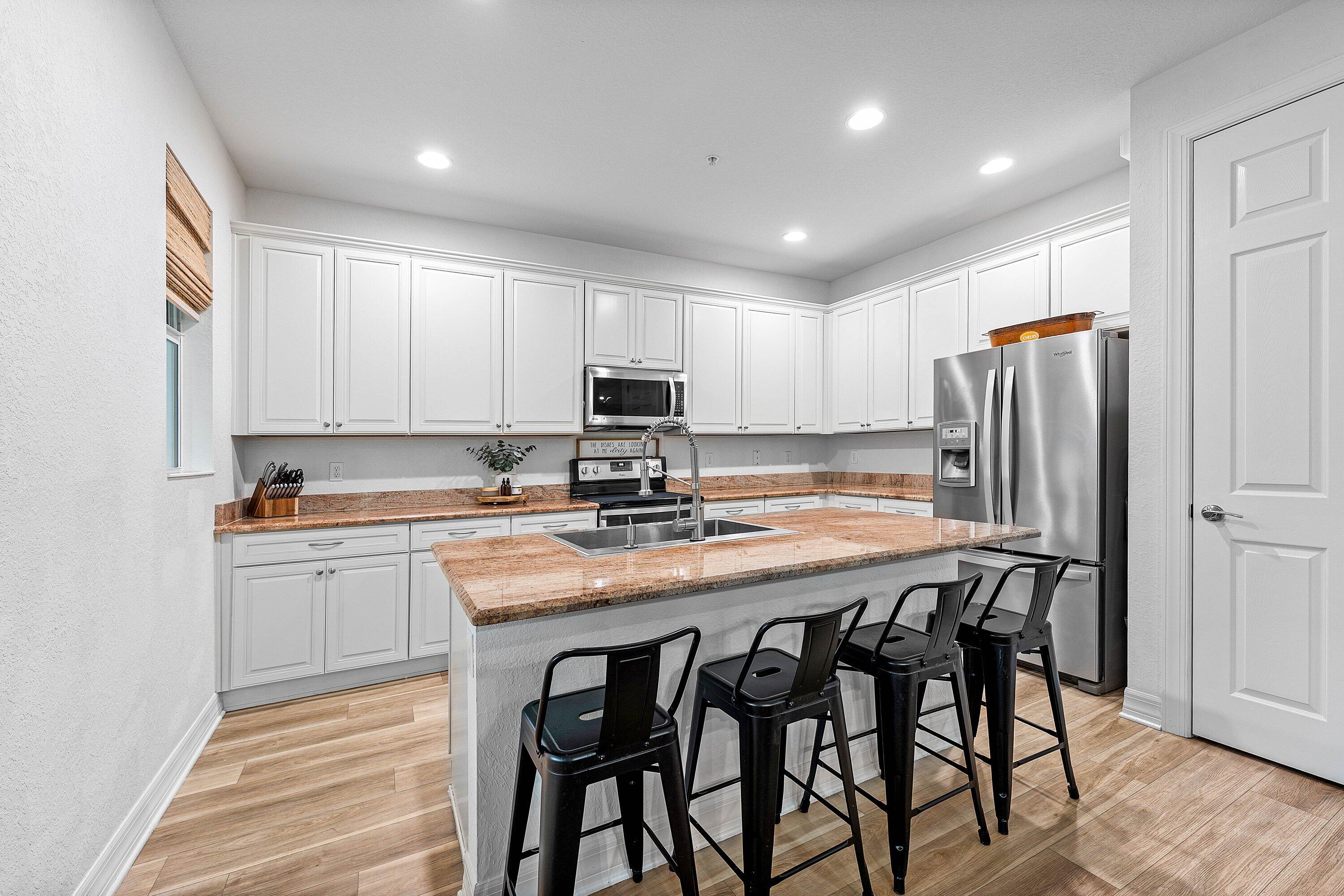 1056 Community Drive Jupiter, FL 33458 - Photo 15 of 50 a kitchen with stainless steel appliances granite countertop a table chairs sink refrigerator and microwave