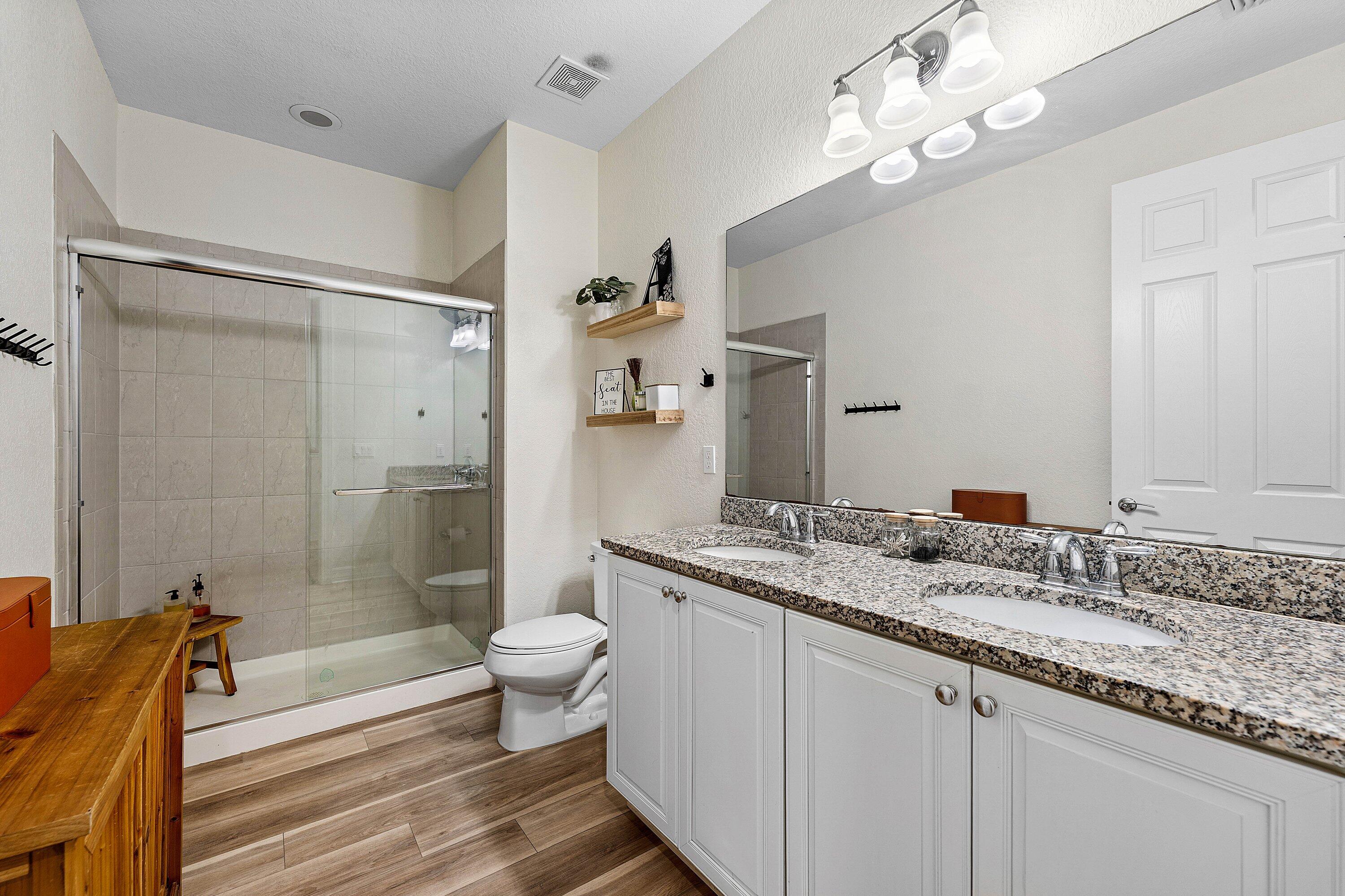 1056 Community Drive Jupiter, FL 33458 - Photo 20 of 50 a bathroom with a granite countertop sink a toilet a mirror and shower