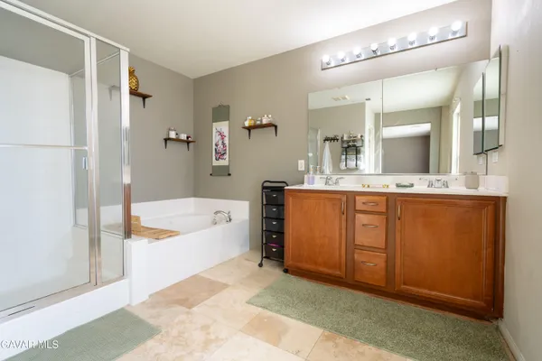 a spacious bathroom with a granite countertop sink a mirror a bathtub and shower
