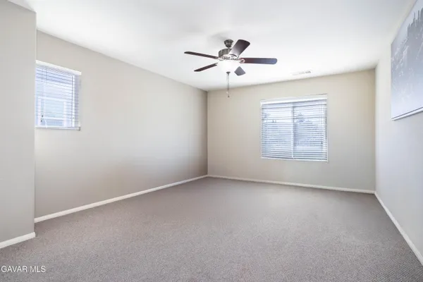 an empty room with windows and fan