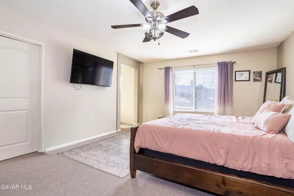 a bedroom with a bed a flat screen tv and a chandelier