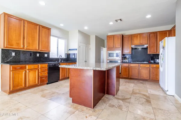 a kitchen with stainless steel appliances granite countertop a stove top oven a sink a refrigerator and cabinets