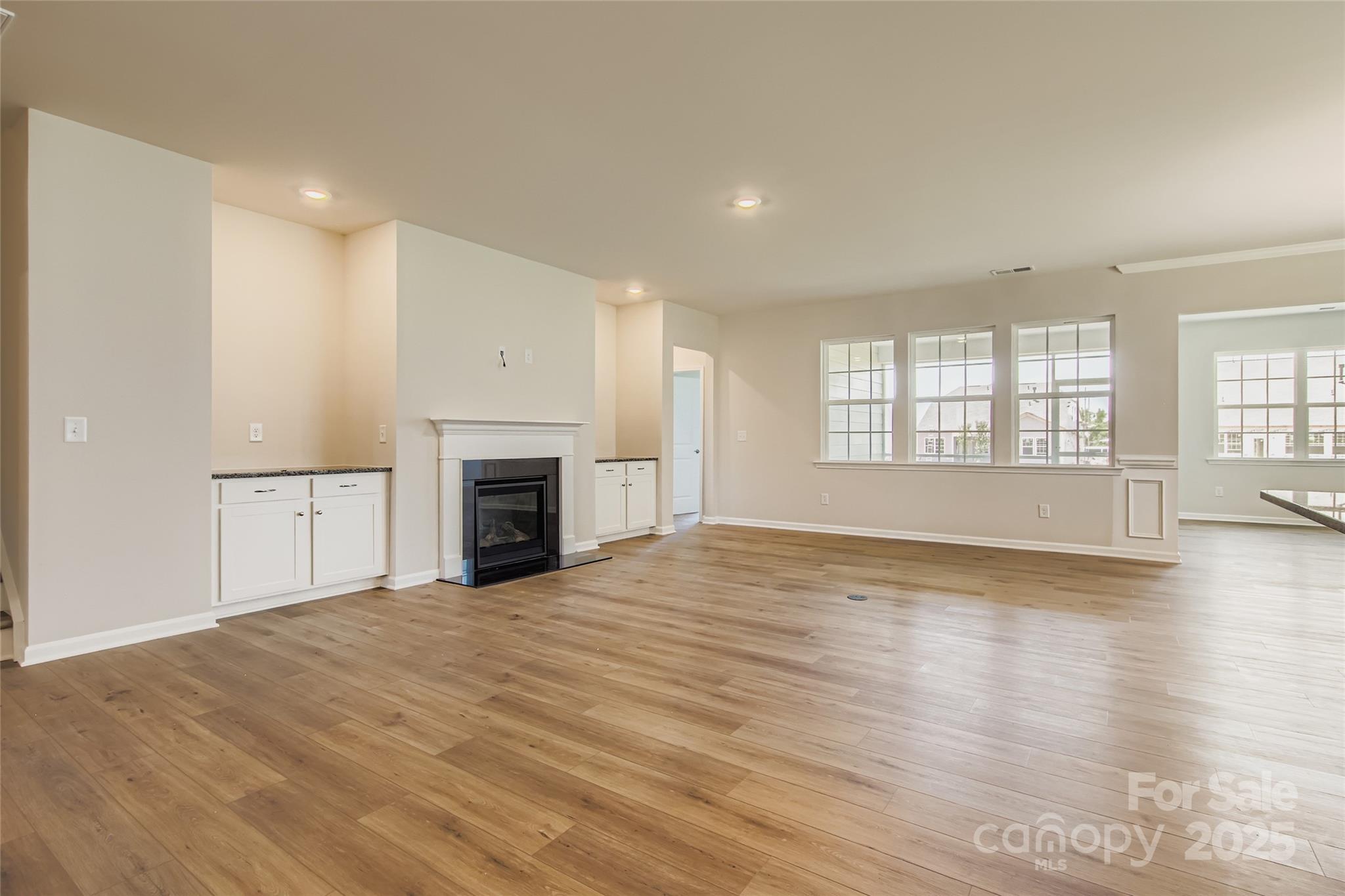 2831 Morning Song Way Lancaster, SC 29720 - Photo 4 of 18 an empty room with wooden floor fireplace and windows
