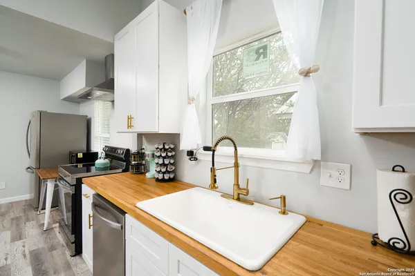 a kitchen with a stove a sink a counter top space and cabinets