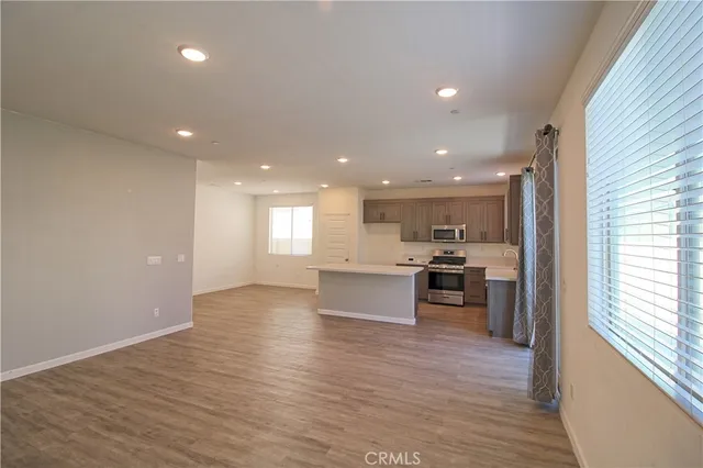 a view of kitchen with kitchen island granite countertop a stove top oven a sink and white cabinets with wooden floor