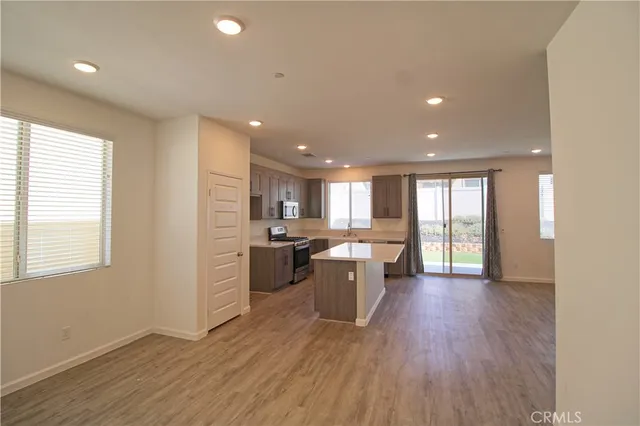 a large kitchen with kitchen island wooden floors wooden cabinets and stainless steel appliances
