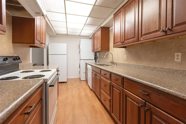 a kitchen with stainless steel appliances granite countertop a refrigerator a sink dishwasher a stove and white countertops with cabinets